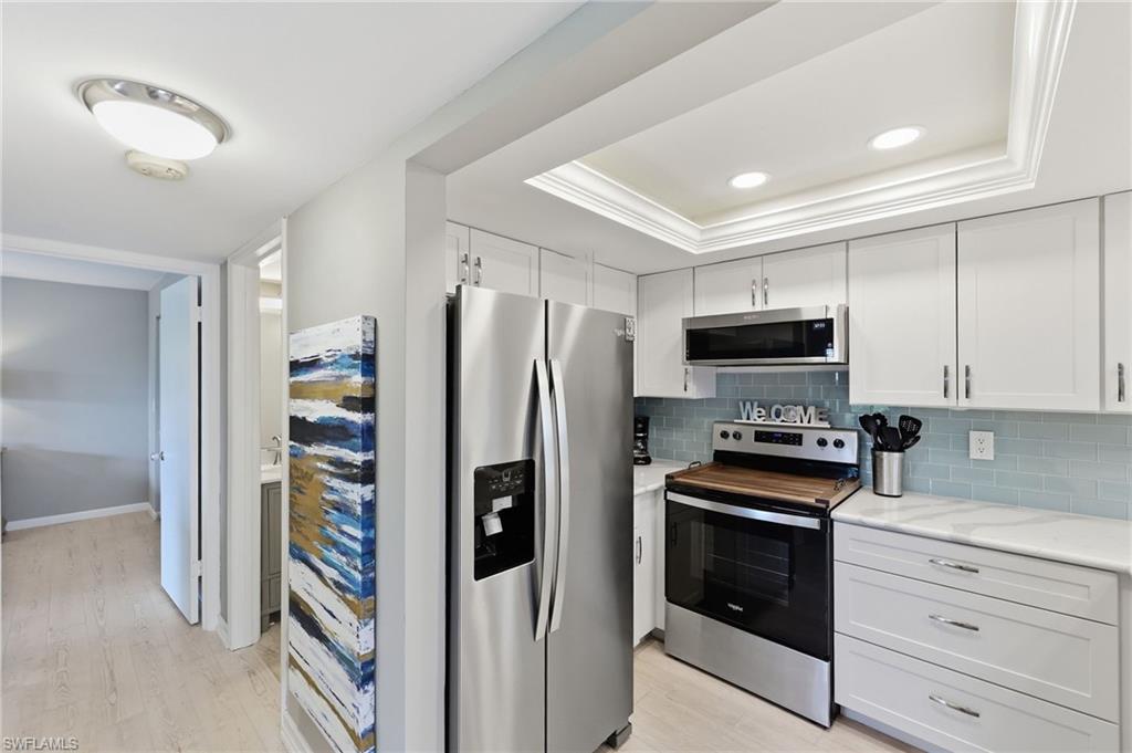 Kitchen featuring white cabinetry, stainless steel appliances, light blue subway tile backsplash, and recessed lighting