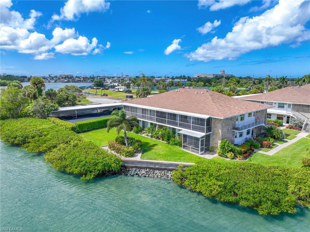 Waterfront multi-story building featuring screened balconies and a brown shingle roof
