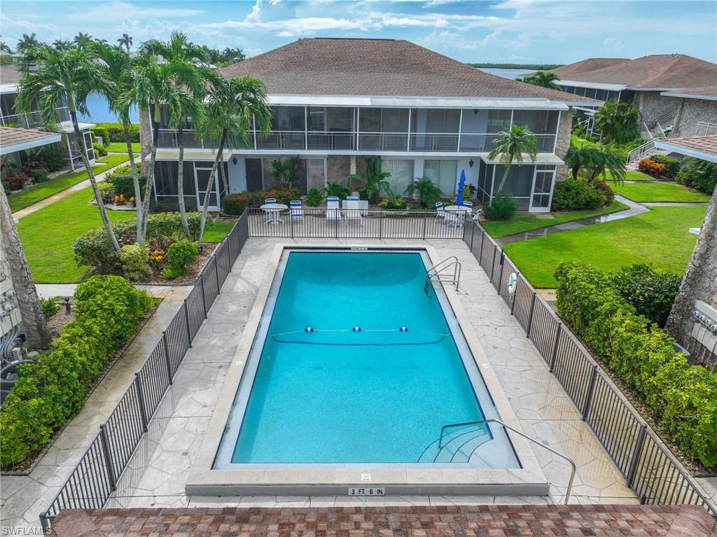 Resort-style rectangular swimming pool with a surrounding stone deck, metal fencing, and integrated steps