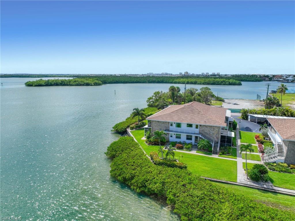 Waterfront property featuring lush green landscaping, mature palm trees, and direct water access