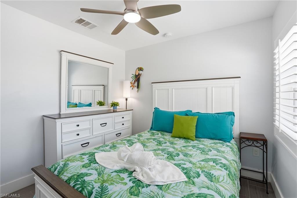 Bedroom featuring a white paneled headboard and a coordinating dresser with dark hardware - Virtually Edited Image