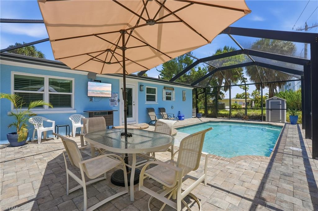 Screened-in pool area featuring a paver deck, a rectangular swimming pool, and a light blue stucco exterior - Virtually Edited Image