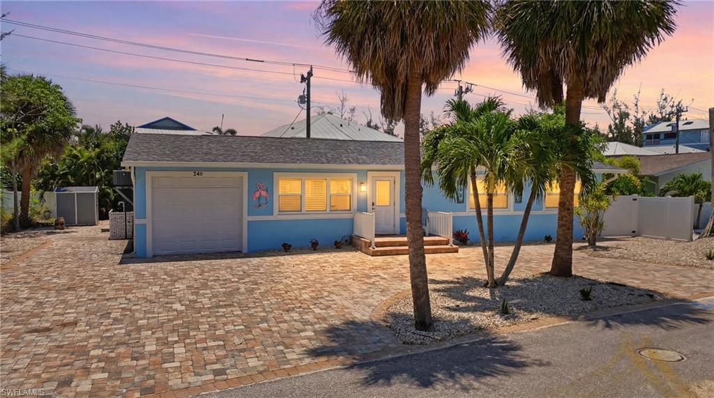 Light blue exterior with white trim featuring a single garage, multiple windows, a front entry with steps, and a paver driveway - Virtually Edited Image