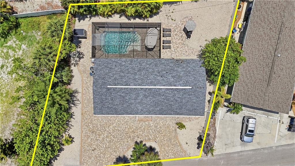 Property featuring a screened-in swimming pool, a spacious paver patio, and mature perimeter landscaping - Virtually Edited Image