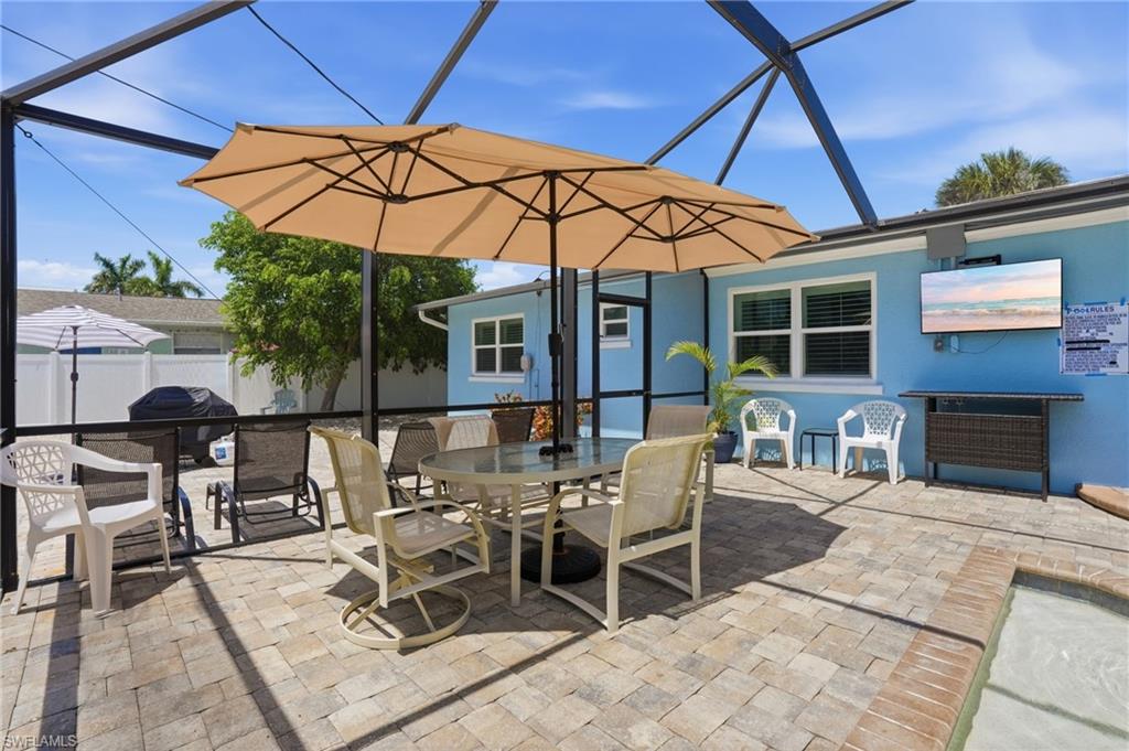 Screened patio featuring paver flooring, a light blue exterior, and a pool border - Virtually Edited Image