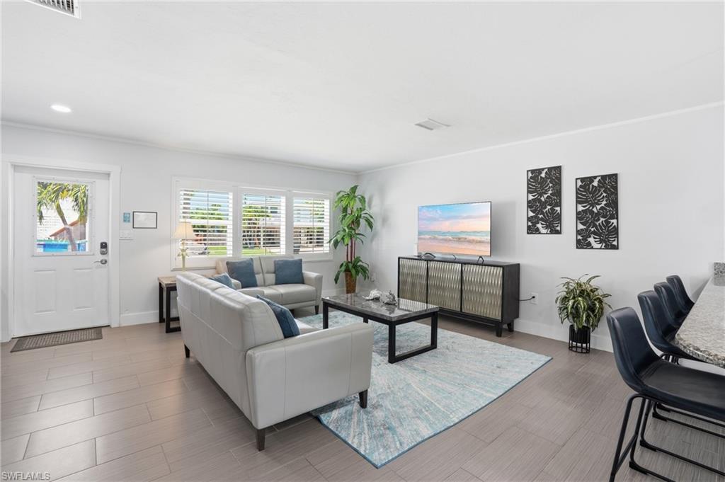Bright living area featuring light-toned tile flooring, white walls, and recessed lighting - Virtually Edited Image