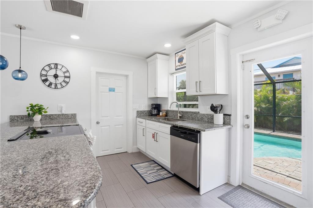 Kitchen featuring white shaker cabinetry, stainless steel appliances, speckled stone countertops, and gray wood-finish flooring - Virtually Edited Image