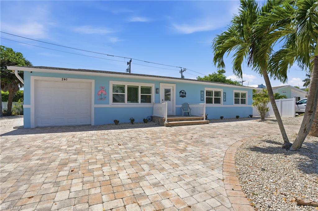 Single-story residence featuring a light blue exterior, white trim, and a paver driveway - Virtually Edited Image