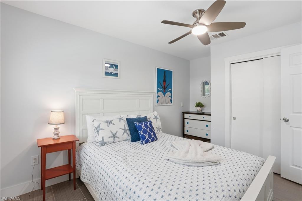 Bedroom featuring a white paneled headboard and wood-finish flooring - Virtually Edited Image