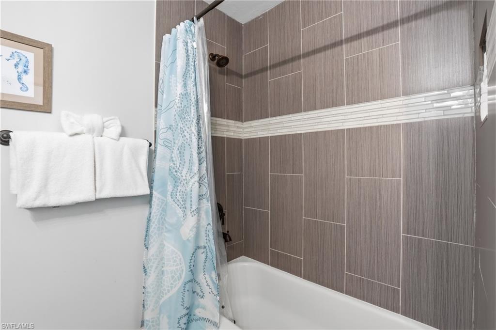 Full bathtub featuring vertically stacked tile walls with a horizontal glass mosaic accent band - Virtually Edited Image