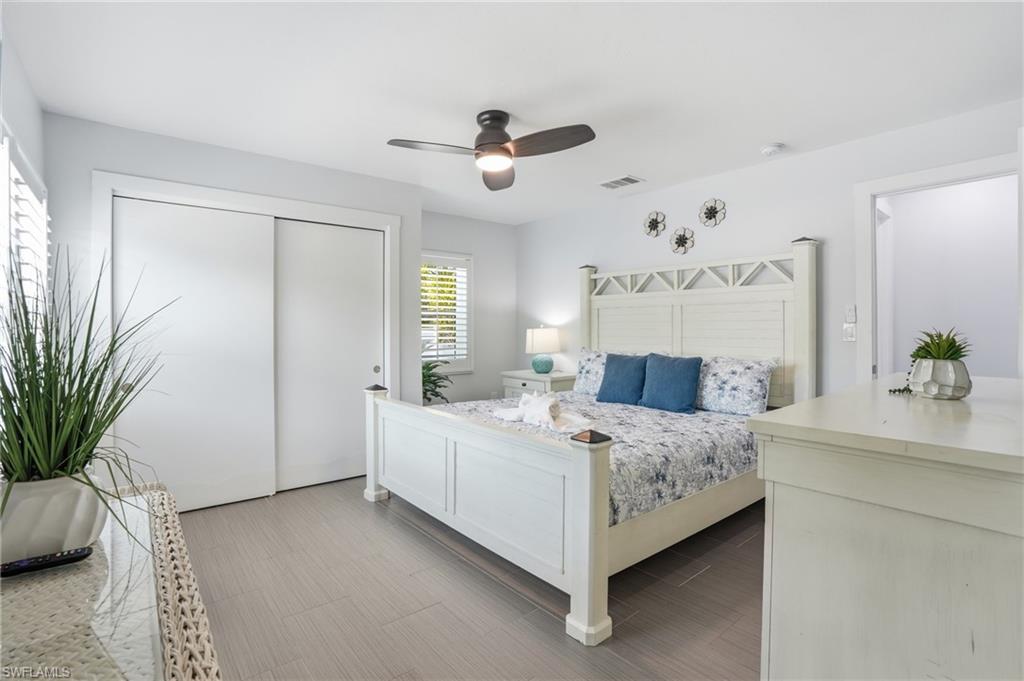 Bedroom featuring wood-finish flooring and white plantation shutters - Virtually Edited Image