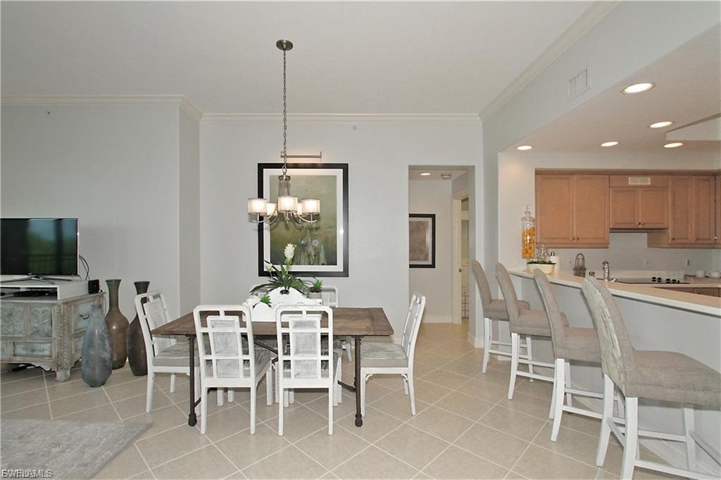 Dining space with crown molding, a chandelier, and light tile patterned flooring