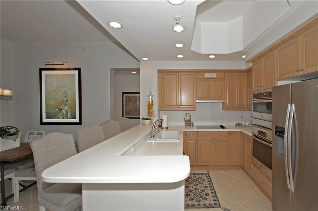Kitchen featuring stainless steel appliances, a peninsula, light countertops, recessed lighting, and a kitchen bar