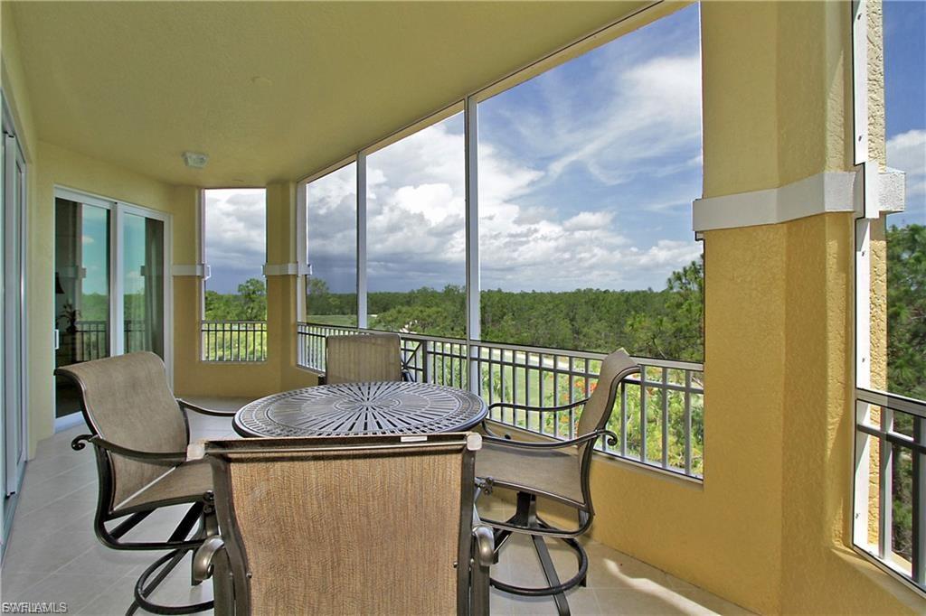 Sunroom featuring healthy amount of natural light, a view of trees, and tile patterned flooring