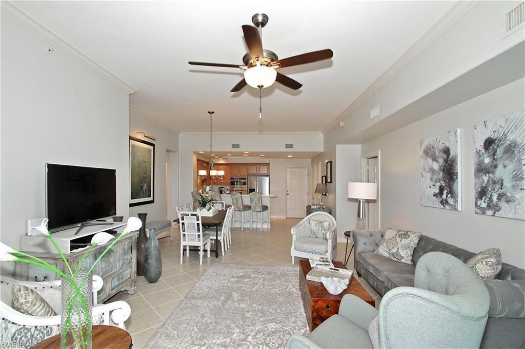 Living room featuring crown molding, ceiling fan, and light tile patterned floors