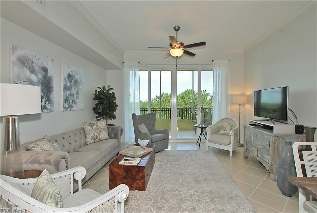 Living room featuring ornamental molding, a ceiling fan, and light tile patterned flooring