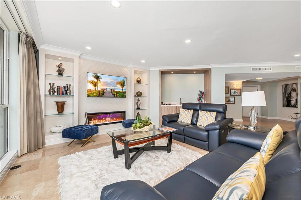 Living room featuring a glass covered fireplace, built in features, recessed lighting, and ornamental molding
