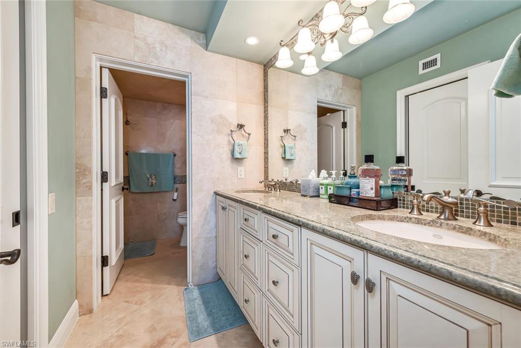Full bath with toilet, a sink, visible vents, and tile walls