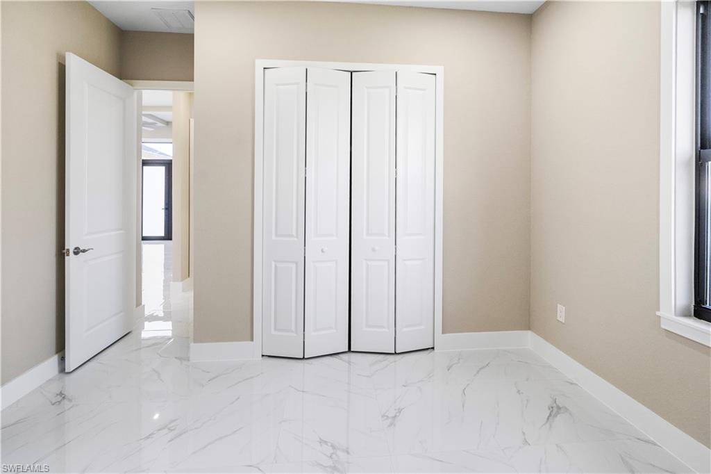 Unfurnished bedroom featuring light marble finish floors and a closet