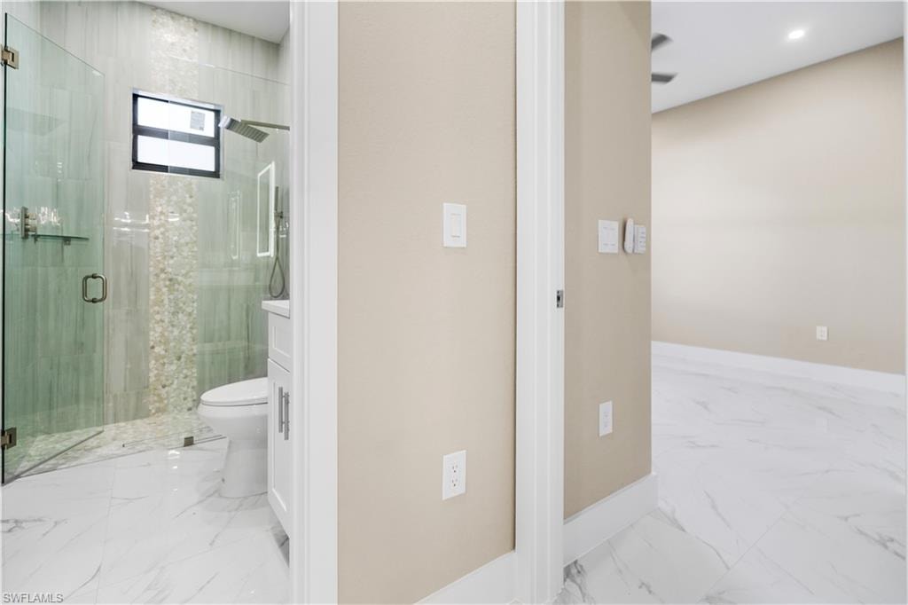 Full bath featuring a marble finish shower, light marble finish floors, and vanity