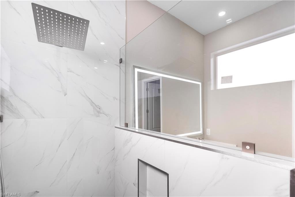 Full bath with a marble finish shower