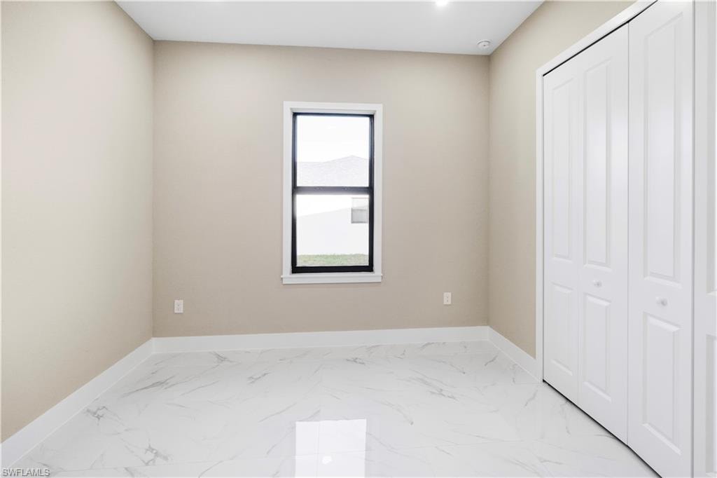 Unfurnished bedroom featuring light marble finish floors and a closet