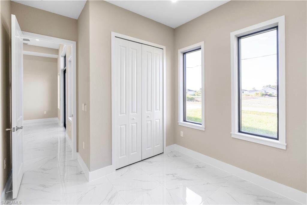 Unfurnished bedroom with light marble finish floors and a closet