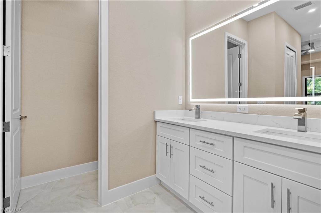 Master Bathroom with double vanity and light marble finish flooring
