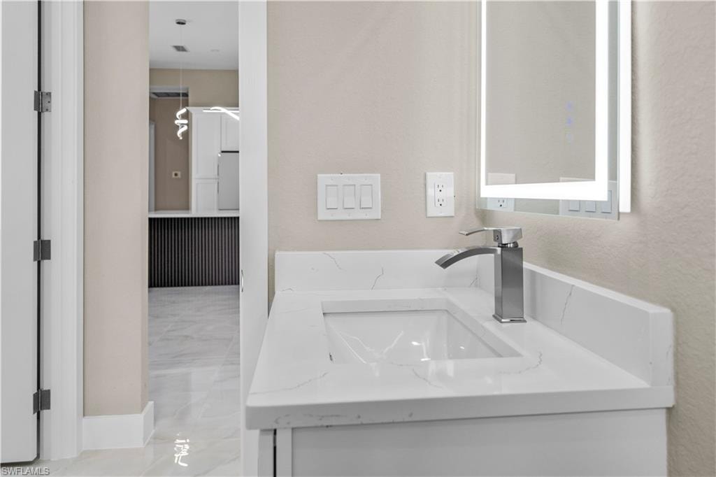 Bathroom with vanity and a textured wall