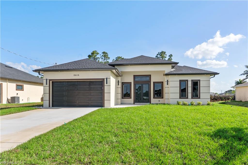 Prairie-style house with a front lawn, concrete driveway, stucco siding, and an attached garage