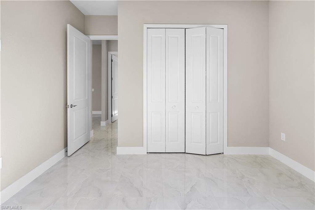 Unfurnished bedroom with light marble finish floors and a closet