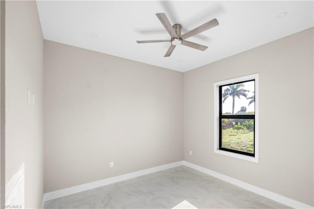Spare room with light marble finish floors and a ceiling fan