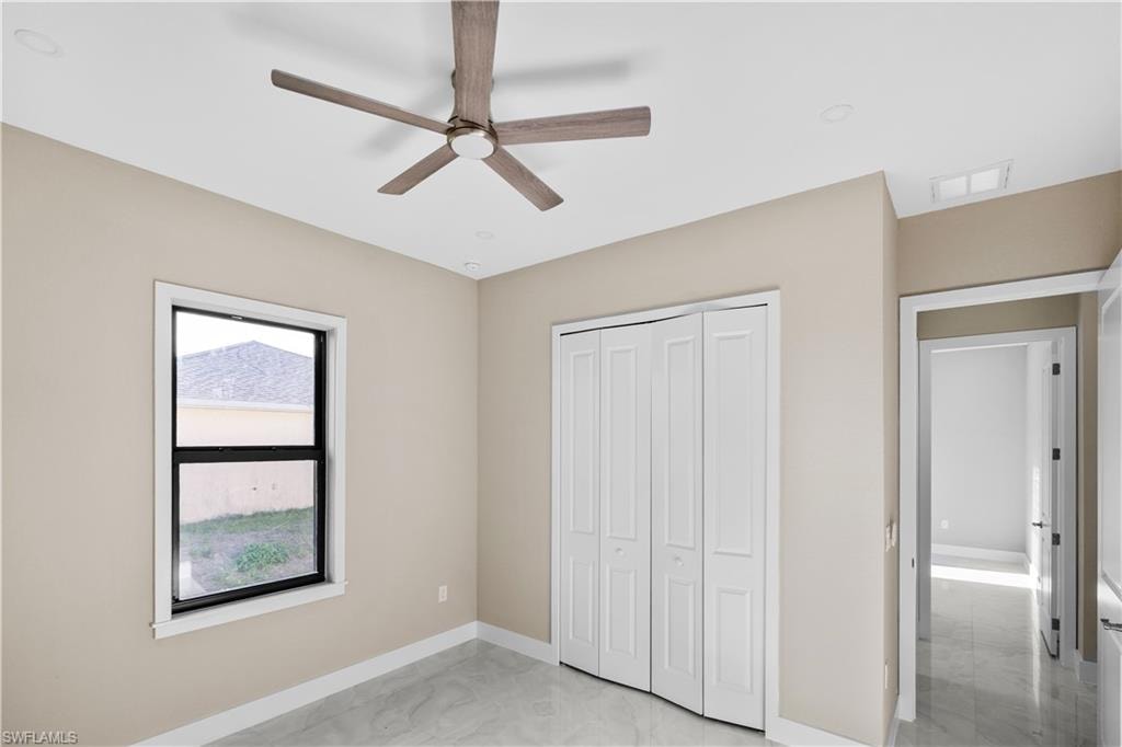 Unfurnished bedroom with a closet, a ceiling fan, and light marble finish flooring