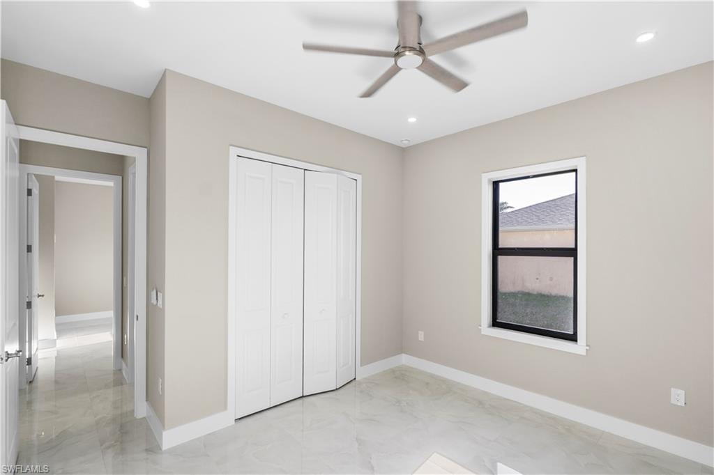 Unfurnished bedroom featuring light marble finish flooring, a ceiling fan, recessed lighting, and a closet