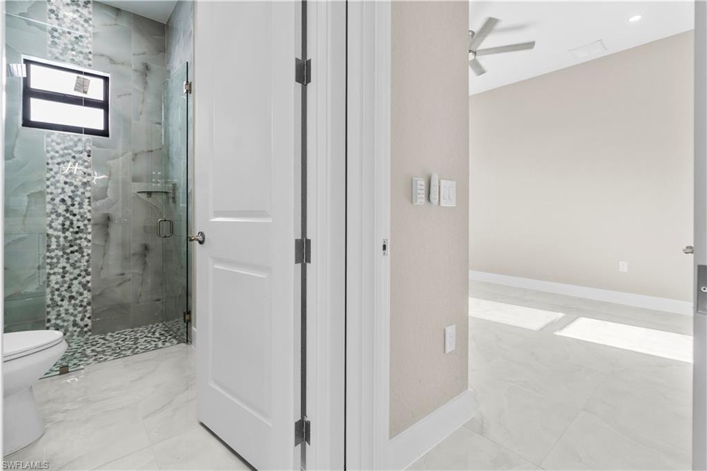 Bathroom with a marble finish shower and a ceiling fan