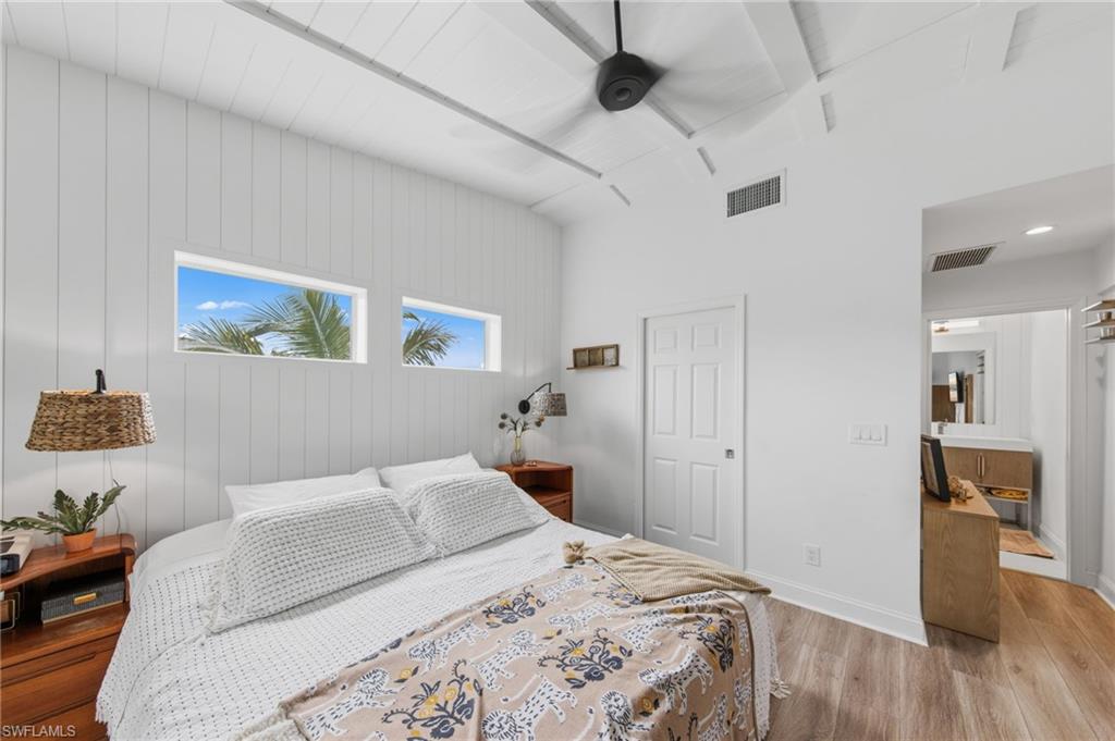 Bedroom with light wood finished floors, ceiling fan, and wooden walls