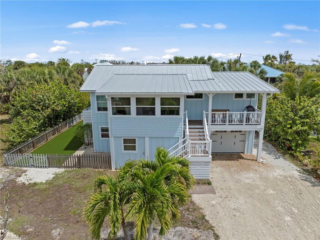 Coastal home featuring driveway, an attached garage, a metal roof, and board and batten siding