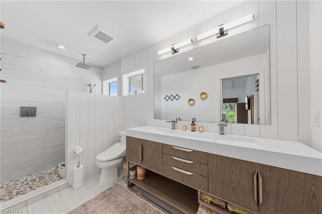 Full bath featuring vanity, a walk in shower, plenty of natural light, and light tile patterned floors