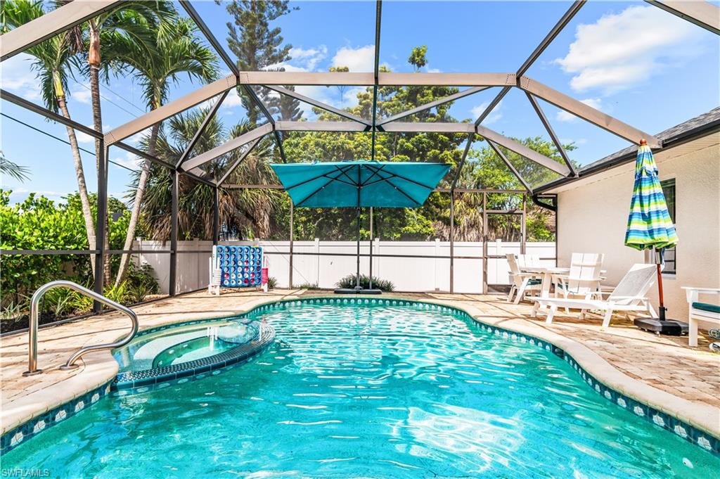 Screened enclosure featuring a freeform swimming pool and integrated spa