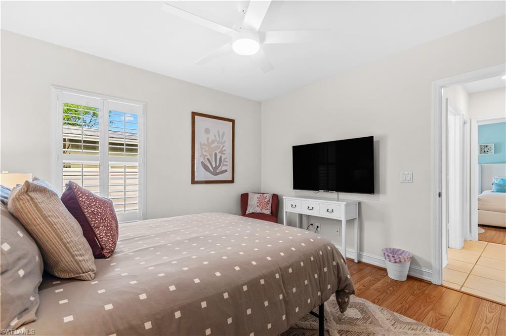 Interior room featuring wood-finish flooring, white walls, and a ceiling fan