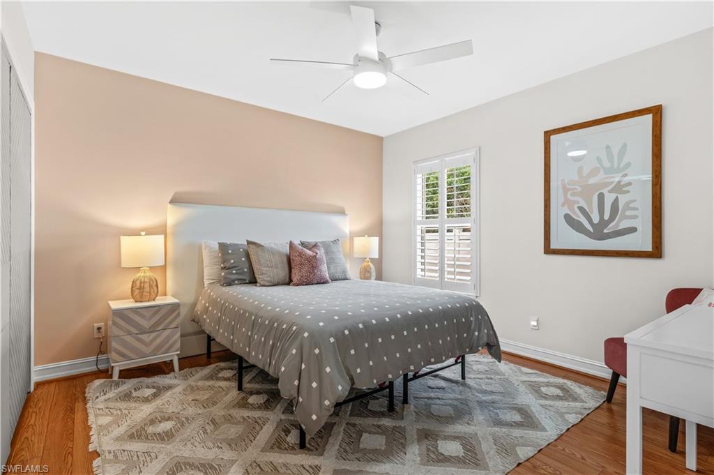 Spacious room featuring wood-finish flooring, a ceiling fan, and plantation shutters