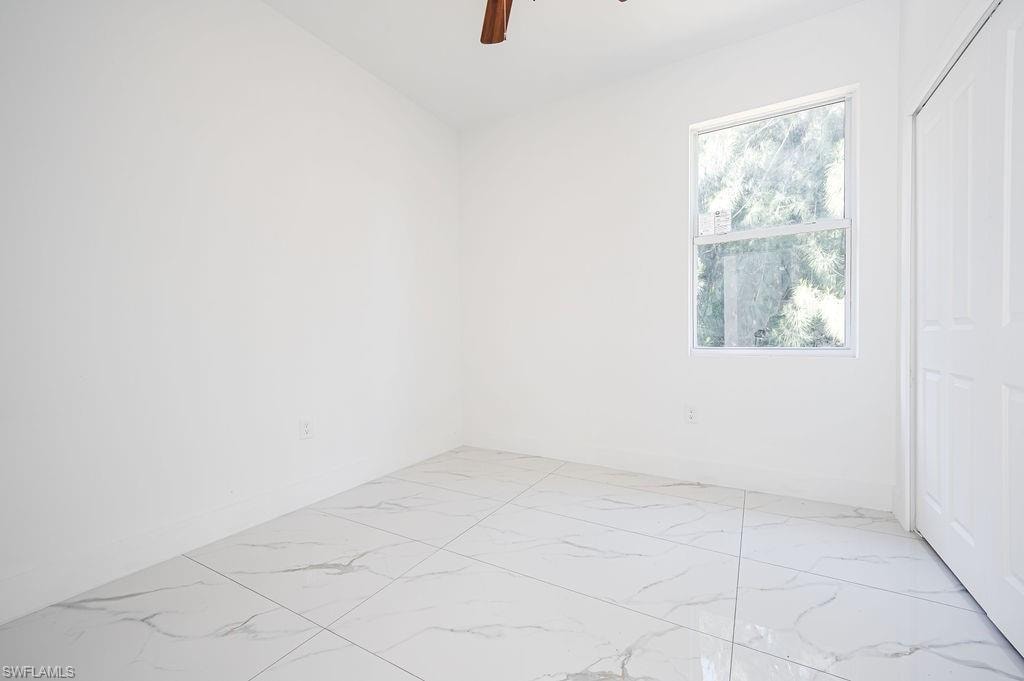 Spare room with light marble finish flooring and a ceiling fan. Photos are of a staged model or similar plan. Features and finishes may vary.