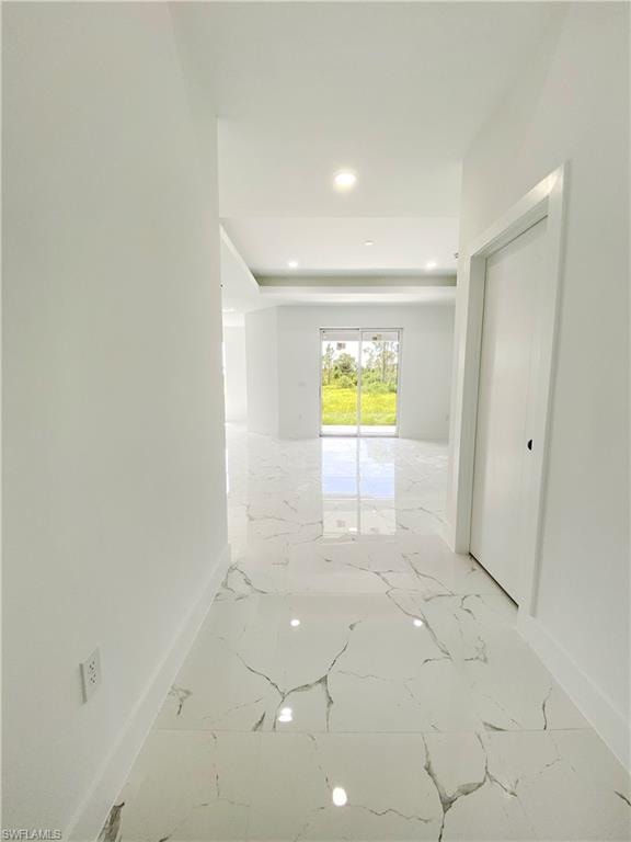 Hallway featuring light marble finish floors, recessed lighting, and a raised ceiling. Photos are of a staged model or similar plan. Features and finishes may vary.