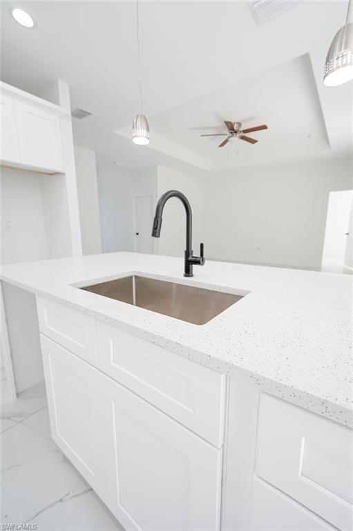 Kitchen featuring white cabinets, pendant lighting, a tray ceiling, and recessed lighting. Photos are of a staged model or similar plan. Features and finishes may vary.