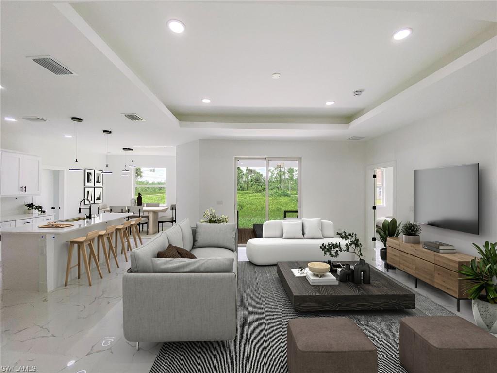 Living room featuring light marble finish floors, a raised ceiling, and recessed lighting. Photos are of a staged model or similar plan. Features and finishes may vary.