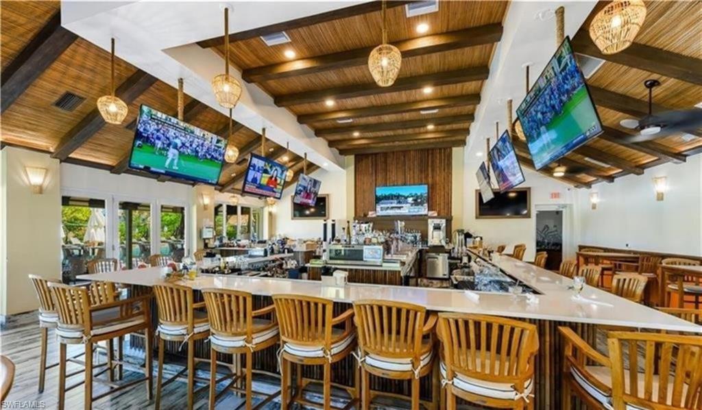 Bar with lofted ceiling with beams, wooden ceiling, decorative light fixtures, and visible vents