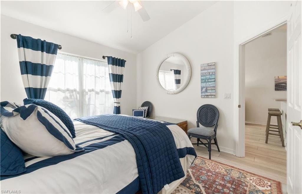 Bedroom featuring baseboards, lofted ceiling, wood finished floors, and ceiling fan