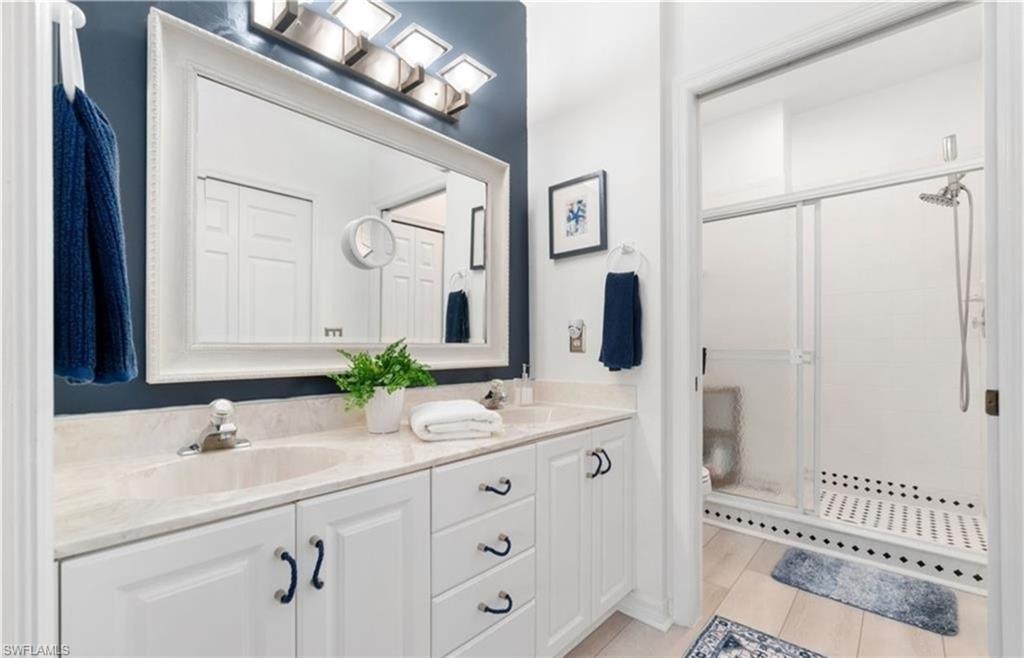Bathroom with double vanity, a sink, toilet, and a shower stall