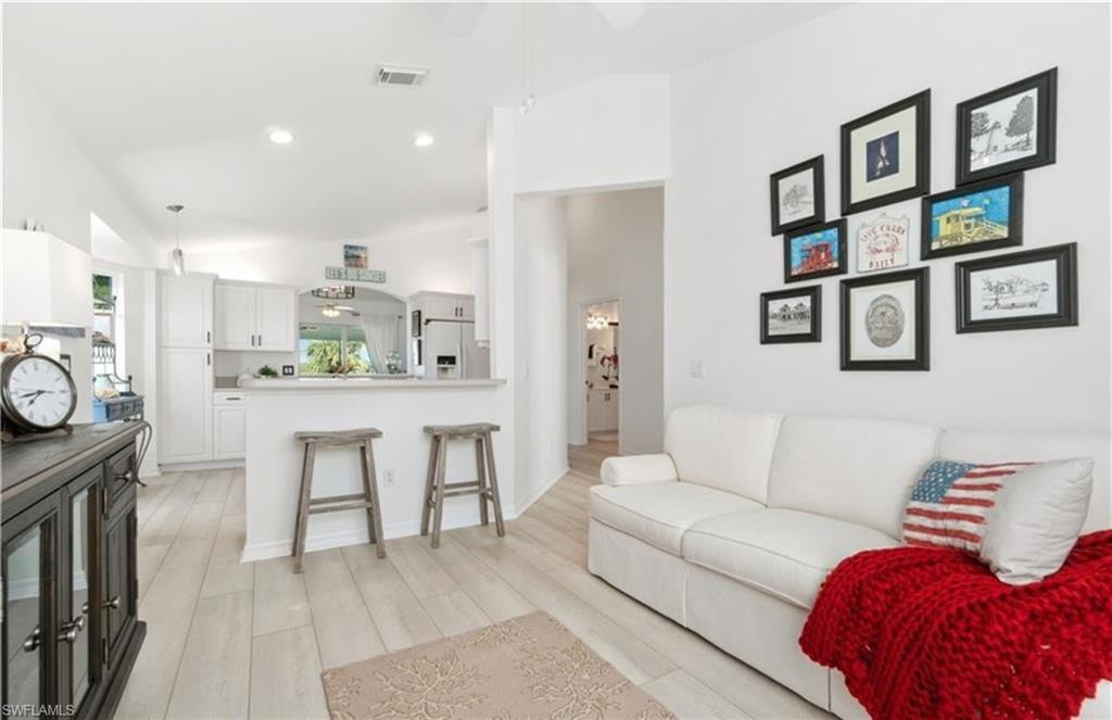 Living area featuring recessed lighting, lofted ceiling, visible vents, and light wood-type flooring
