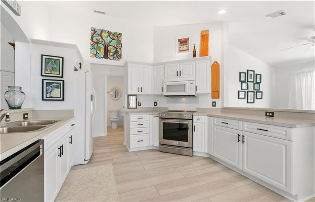 Kitchen featuring a sink, a peninsula, stainless steel appliances, visible vents, and arched walkways